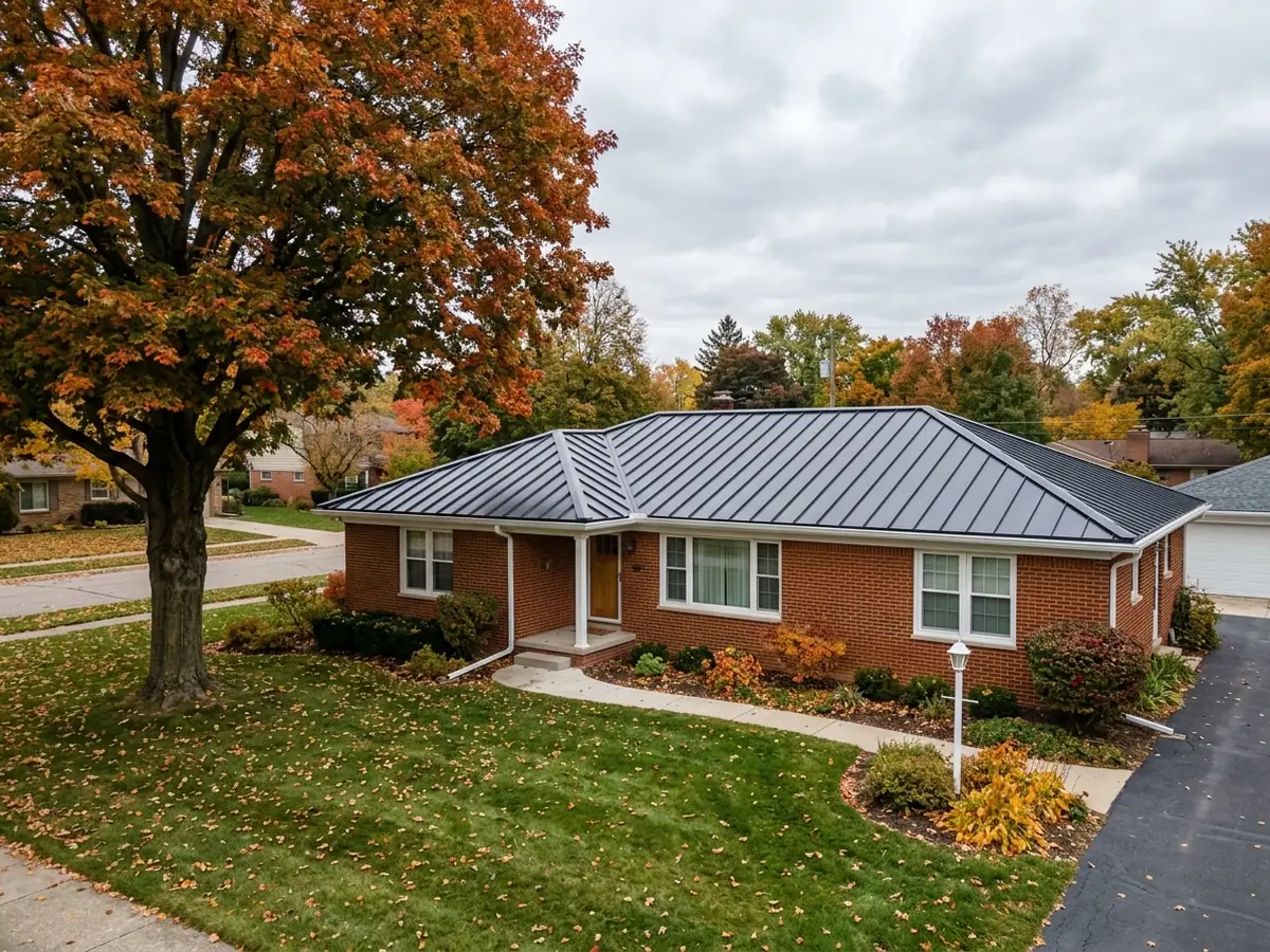 Charcoal snap-lock standing seam steel panels running from the eave to the ridge of a brick ranch house